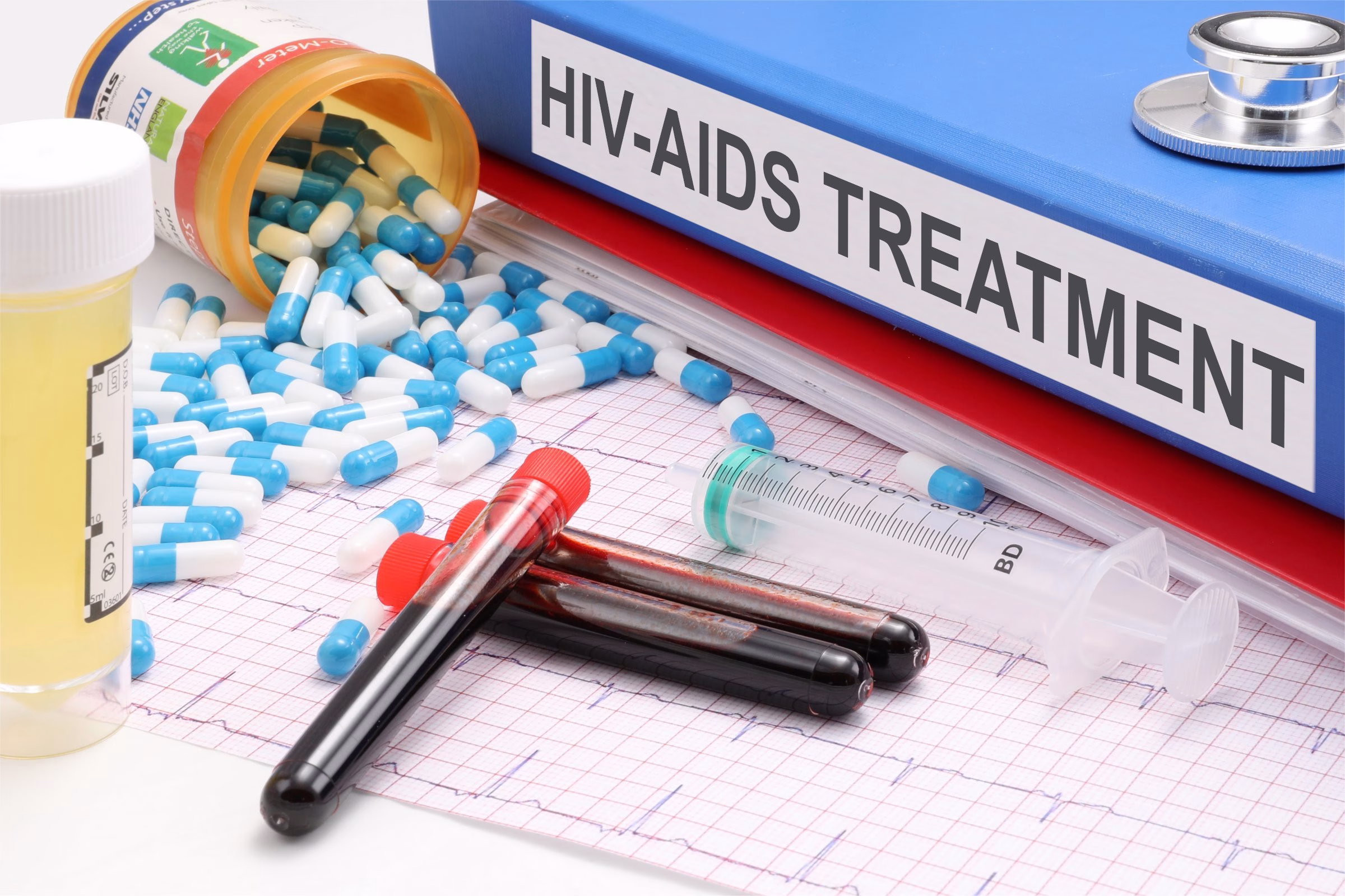 A picture of a file with hiv aids treatment written on the spine together with capsules, blood samples, syringe and an ECG chart.